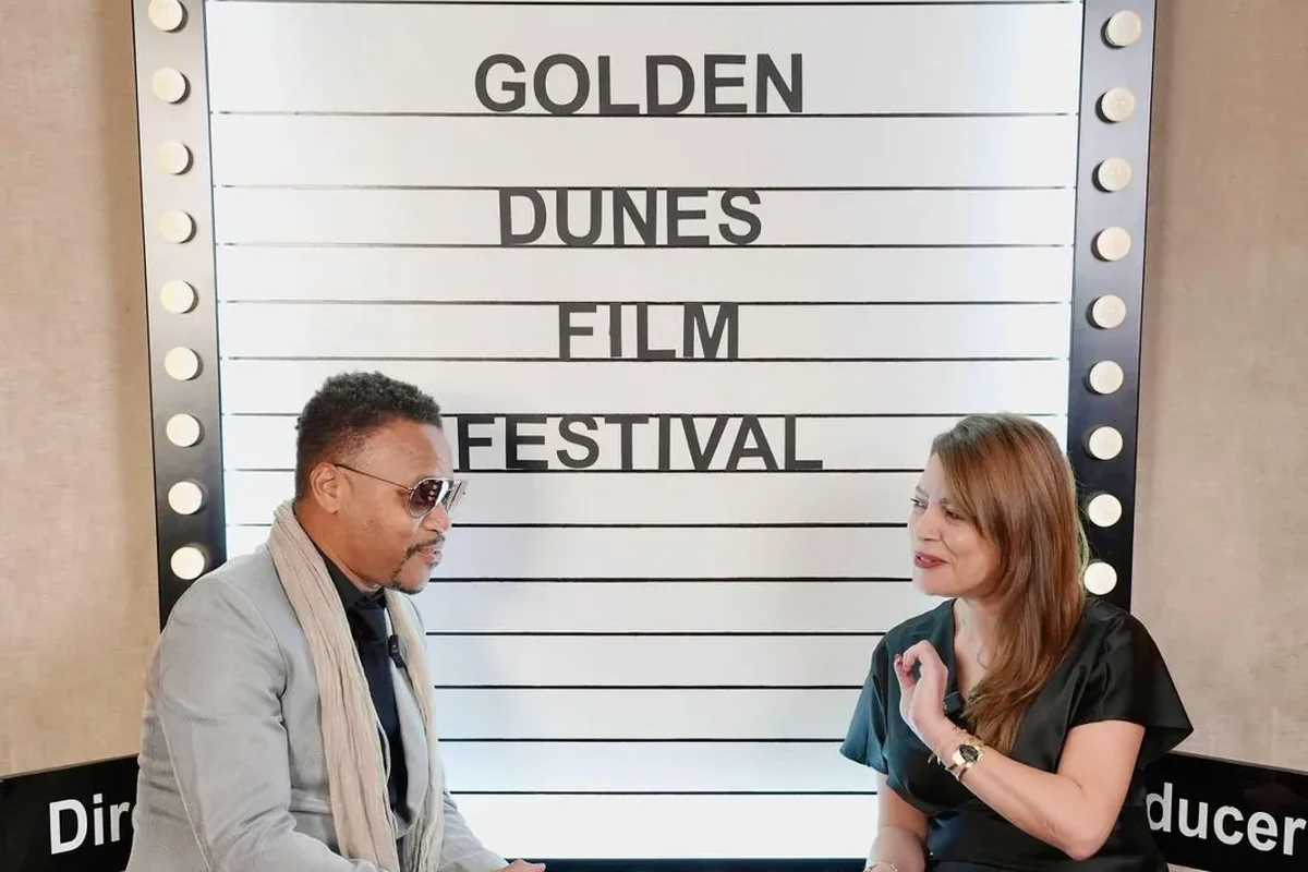 Two people in conversation on the interview stage beneath the Golden Dunes festival marquee